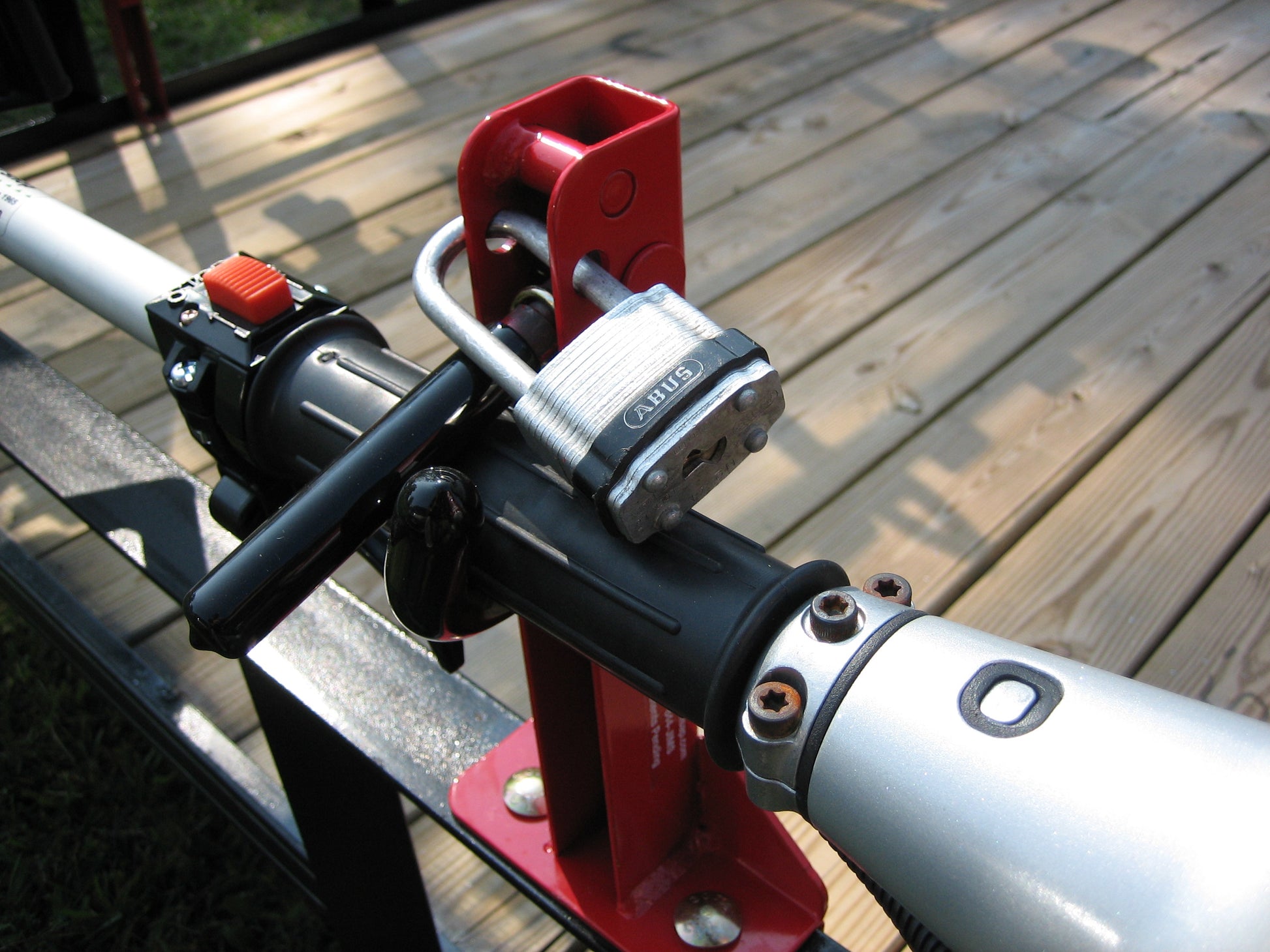 Close-up of a heavy-duty padlock secured through the Jungle Jim’s 1TR trimmer rack handle, protecting landscaping equipment from theft on an open trailer.
