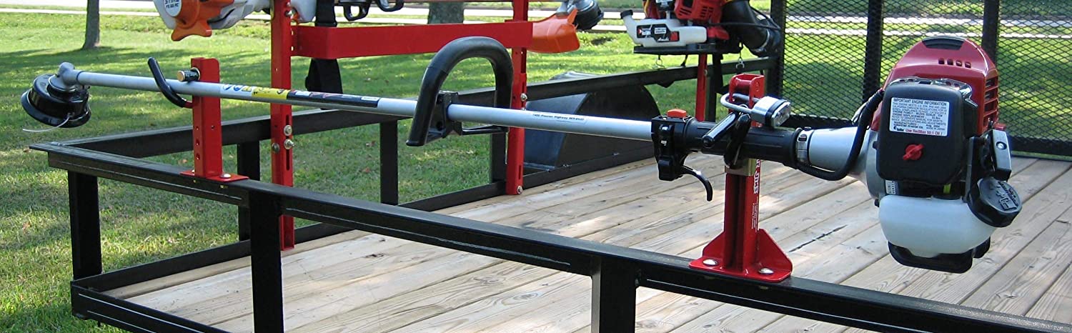 Side view of a Jungle Jim's 1TR trimmer rack bolted to the top rail of an open landscaping trailer.